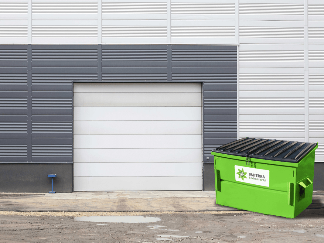 Emterra Environmental Front End Bin with Black Lid Outside a Commercial Building